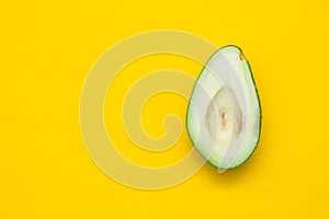 Halve of avocado on a yellow background. Top view. Copy, empty space for text