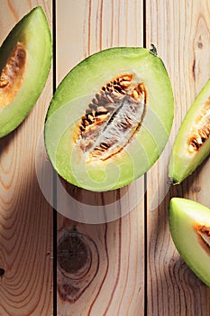 Halve melon and slices on wooden table.