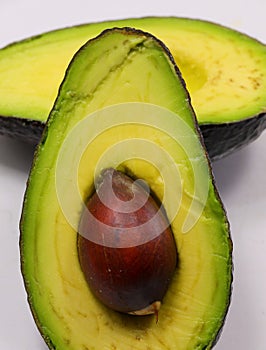 Halved avocado with large seed inside, ideal as healthy eating and wellness concept