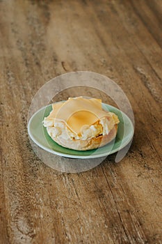 A halved bagel with poppy seeds, scrambled eggs, and cheese on a green plate