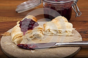 Halved croissant with cherry marmalade on wooden plate