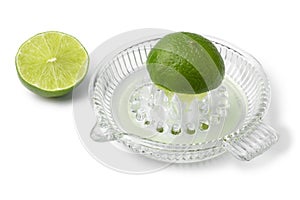 Halved fresh lime and a glass juicer close up on white background