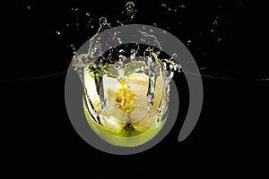 Halved green apple falling into water with splash