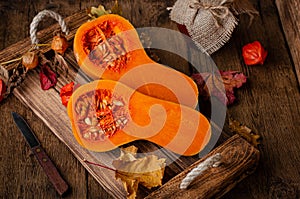 Halved orange pumpkin on rustic wooden tray. Dieting healthy food and rural still life