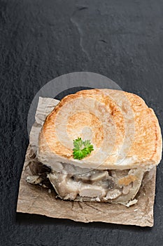 Halved pukka pie pasty on black stone background