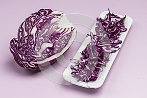 Halved red cabbage, sliced cabbage on on white plate. Vegan food