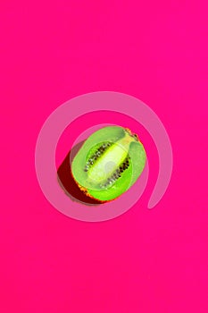 Halved Ripe Juicy Kiwi on Fuchsia Pink Background. Bright Harsh Sunlight Deep Shadow. Vibrant Neon Colors. Summer Tropical