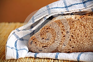 Halved rye bread loaf wrapped in the kitchen towel