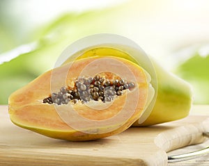 Halved and whole papaya on a wooden board