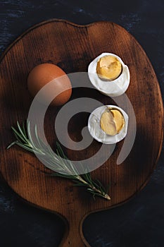 Halves of boiled egg on a wooden cutting board.