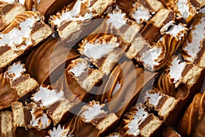 Halves of cakes with cookies and custard in caramel and chocolate close-up. Background of sweets with cream curls