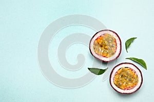 Halves of fresh ripe passion fruit maracuya with leaves on light background, flat lay. Space for text