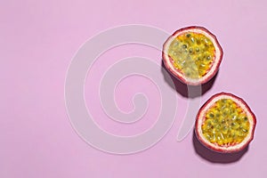 Halves of passion fruit maracuya on pink background, flat lay. Space for text