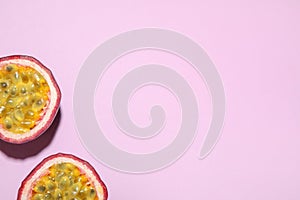 Halves of passion fruit maracuya on pink background, flat lay. Space for text