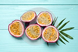 Halves of passion fruits maracuyas and palm leaf on light blue wooden table, flat lay