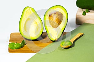 Halves of Ripe Avocado and micro green on wooden podium and stands served on table, white background, Healthy oily food