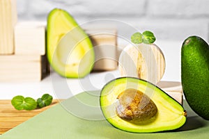 Halves of Ripe Avocado and micro green on wooden podium and stands served on table, white background, Healthy oily food