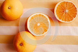 The halves of ripe, sweet oranges are laid out on a striped orange background. The healthy eating and diet, promoting the