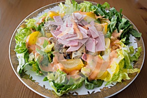 Ham, artichokes and orange tomatoes making a salad meal with lettuce and salad sauce
