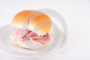 Ham bread roll or bap on a white plate