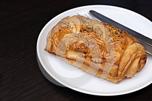 Ham and cheese puff pastry pie, serving on white round ceramic plate. Selective focus