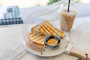 Ham cheese sandwich with custard sauce and ice coffee on marble