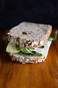 Ham cheese sandwich with kraftkron bread and lettuce on wooden table. Sandwich is a perfect breakfast in a working working day