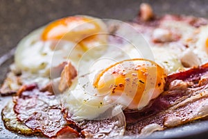 Ham and Eggs. Bacon and Eggs frying on ceramic pan. Salted egg and sprinkled with red pepper. English breakfast