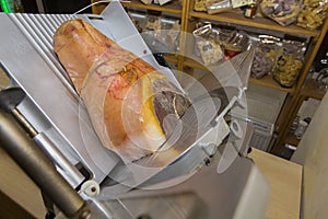 Ham on an electric meat slicer in an Italian shop