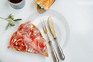 Ham and flavor spices, thinly sliced on a white table with bread. close up. Copy space