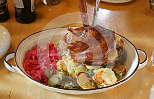 A ham hock or hough or pork knuckle with cabbage, potatoes and pickles