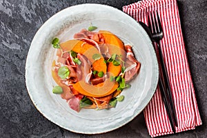 Ham jamon, melon and arugula salad on grey plate
