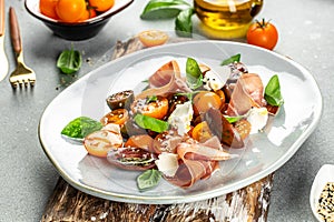 ham prosciutto, cherry tomatoes and cream cheese with basil leaves, antipasto appetizer salad. place for text, top view