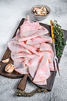 Ham Thin sliced on wooden cutting board with herbs. White background. Top view