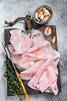 Ham Thin sliced on wooden cutting board with herbs. White background. Top view