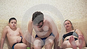 Hamam, family in the Turkish sauna, mom and her son sit on the bench. Father comes in and sits next to him.