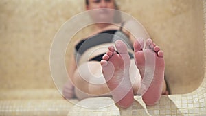 Hamam, family in the Turkish sauna, a woman sitting on the bench. Close - up of her foot.