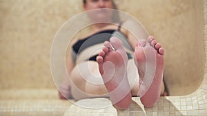 Hamam, family in the Turkish sauna, a woman sitting on the bench. Close - up of her foot.