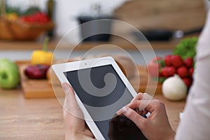 Haman hands using touch pad in the kitchen. Closeup of woman making online shopping by tablet computer and credit car