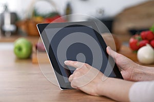 Haman hands using touch pad in the kitchen. Closeup of woman making online shopping by tablet computer and credit car