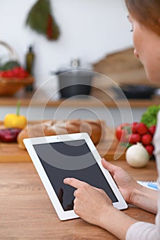 Haman hands using touch pad in the kitchen. Closeup of woman making online shopping by tablet computer and credit car