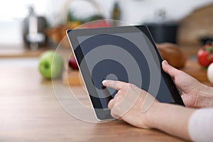 Haman hands using touch pad in the kitchen. Closeup of woman making online shopping by tablet computer and credit car