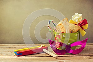 Hamantaschen cookies in bucket with grogger noise maker and carnival mask. Gift for purim festival