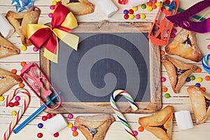 Hamantaschen cookies and chalkboard on wooden white table. View from above