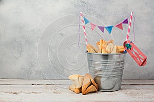 Hamantaschen cookies or hamans ears in bucket over rustic background for Jewish holiday Purim