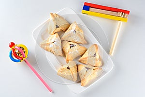 Hamantaschen cookies and wooden noisemaker or gragger on white background. Purim holiday celebration.Top view.