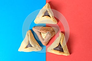 Hamantash filled-pocket cookie recognizable for triangular shape for Jewish holiday of Purim on red and blue background.