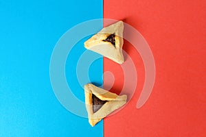 Hamantash filled-pocket cookie recognizable for triangular shape for Jewish holiday of Purim on red and blue background.