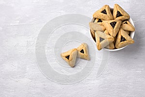 Hamantashen cookies or Aman ears, triangular cookies with poppy seeds on gray background
