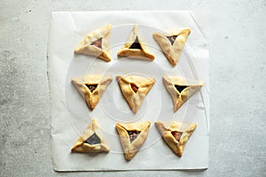 Hamantashen cookies - traditional festive baking for Purim.  Triangle cookie  with different fillings on a baking paper. Top view